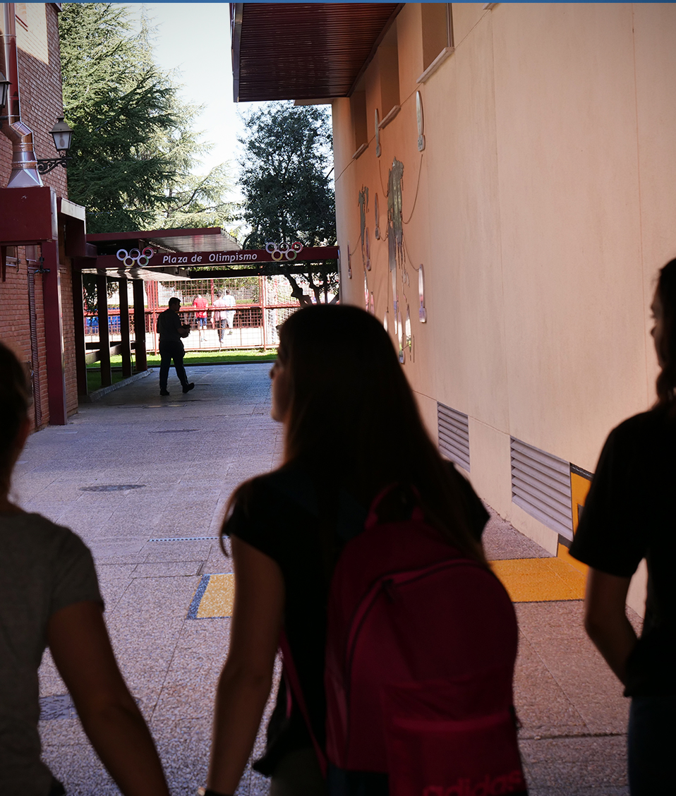 Estudiantes de la Facultad de CIencias del Deporte caminando por los espacios exteriores situados a la sombra